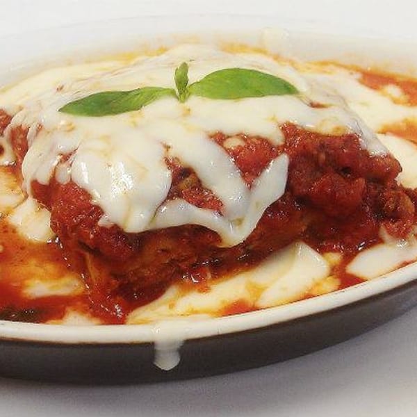 Close-up of La Bella Italia's lasagna, topped with melted mozzarella, rich red sauce, and a basil leaf.